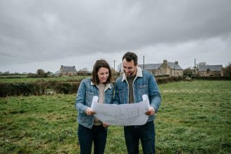 Couple examinant des plans d'architecte sur un terrain à vendre en périphérie de Rennes avant la construction d'une maison