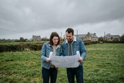 Couple examinant des plans d'architecte sur un terrain à vendre en périphérie de Rennes avant la construction d'une maison