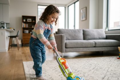 Jeune fille souriante avec aspirateur jouet dans un salon moderne